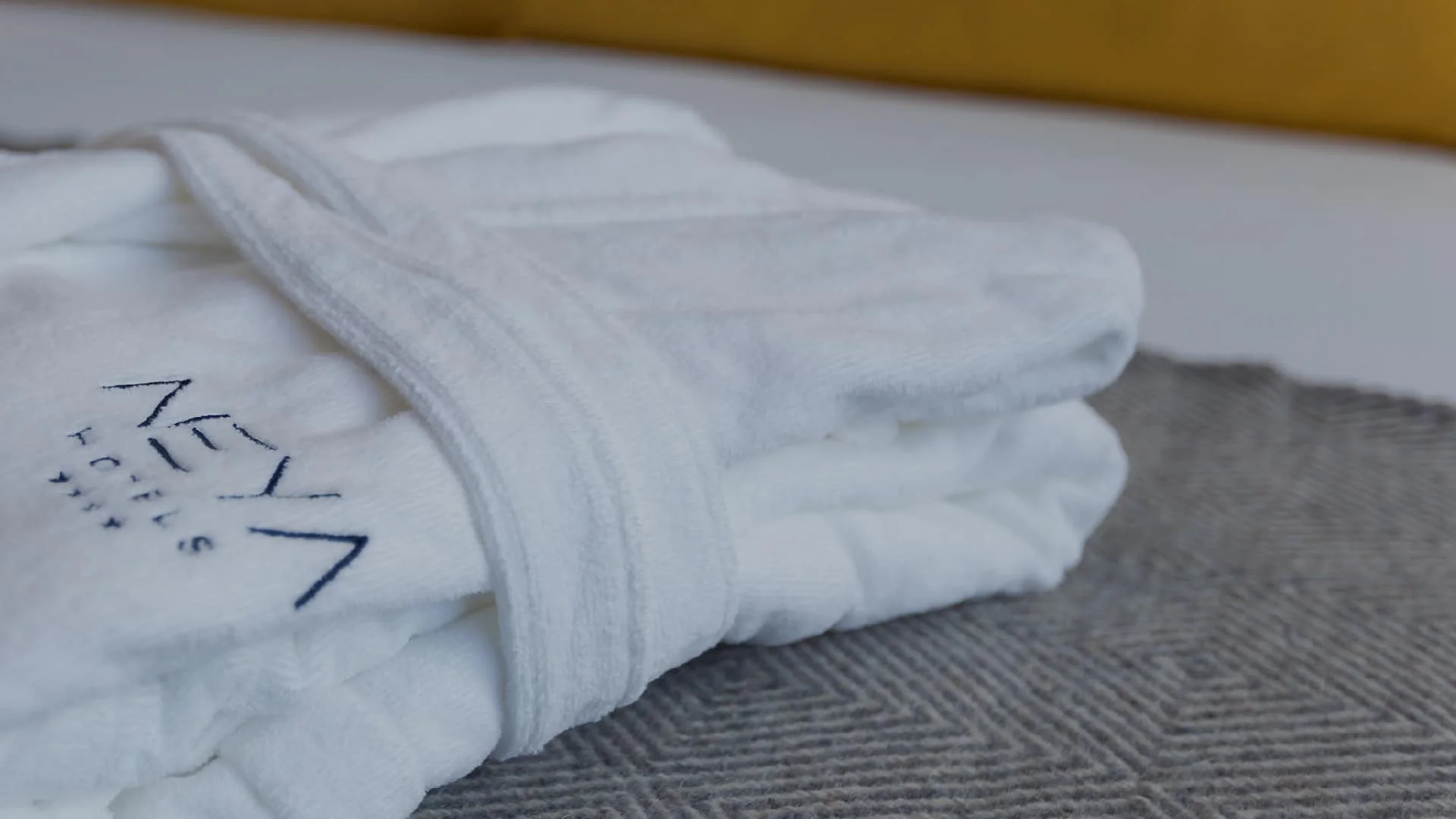 Roupão com logotipo NEYA Porto Hotel em cima da cama